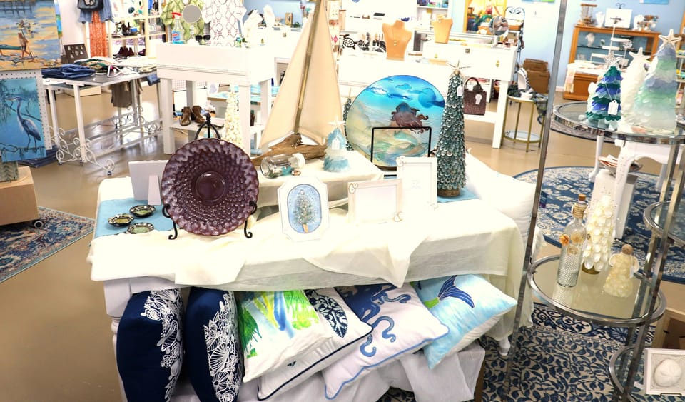 Coastal decor table with a model sailboat, glass art and ocean pillows
