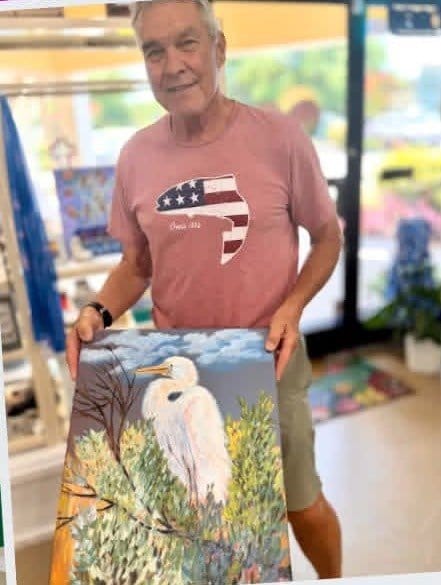 A local painter holding his egret painting inside the shop