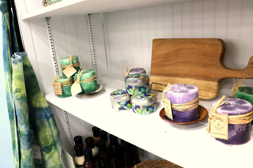 Handmade candles and a wooden cutting board on a white shelf